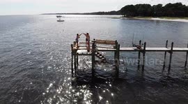 teenagers flip off dock into ocean
