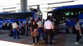 Typhoon Jebi-affected, stranded passengers from Kansai International Airport board the airport limousine bound for Osaka while airport personnel answers queries from other passengers