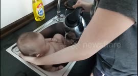 Mom helps baby bathing in washing basin