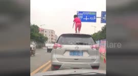 Girl stands on the top of car after climbing out of sunroof