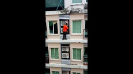 Workman in Thailand casually fixes air con seven floors up without a harness