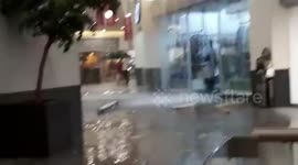 Bemused shoppers walk by 'river' inside flooded mall after roof collapsed