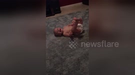 Diapered baby attempts his first somersaults all by himself