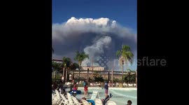 Huge pyrocumulus cloud from Charlie Fire looms above pool-splashing families at Six Flags