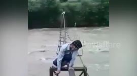 Students in India cross flooded river crawling on top of shaky pipeline