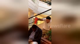 Hilarious mall prankster balances soda cup on back of sleeping man's head