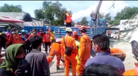 Workers remove body bags as rescue operations at Palu hotel continue