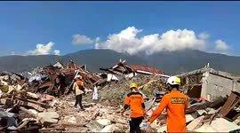 Rescuers walk through piles of rubble in aftermath of deadly Indonesia earthquake