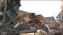 Excavator digs through debris from fallen hotel on earthquake-stricken Indonesia island