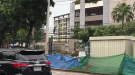 Thai workman stands on overhead power cables