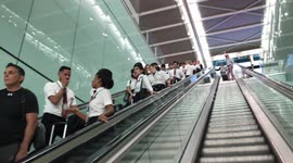 Long row of cabin crew on an escalator at Heathrow