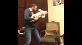 Father pretends to hold baby like a shooting rifle