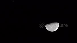 A UFO flies past the moon, casting a shadow over it.