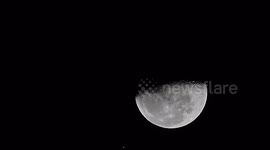 A UFO casts a dark shadow as it floats past the full moon.