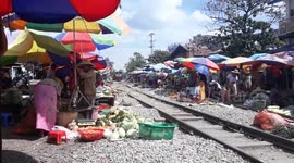 Train crossing the market and people need to hurry bring their stuff aside