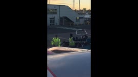 Man films baggage handlers throwing luggage onto a cart