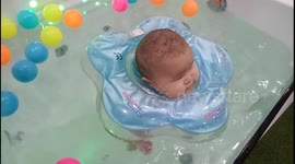 Cute chubby baby floating on water at baby spa