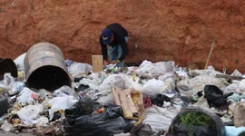 Young man searches through garbage in Caracas slum area