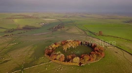 Dawn breaks over ring of autumnal trees in the Peak District in breathtaking drone footage