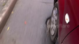 Pothole on road showing  wheel of car running over it.