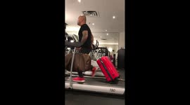 Man holds suitcases while running on a treadmill in Vietnamese gym