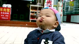 Cute baby eats noodles dangled by mother