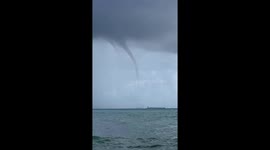 Water spout looms low over cargo ship