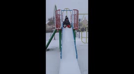 Boy slides down snow covered slide in Weymouth