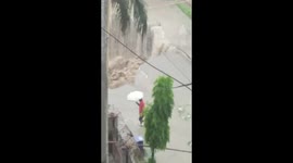 Man walking on road prevents himself from hazard due to rain in Delhi