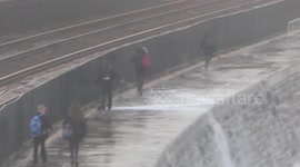 Children risking their lives by dodging huge waves on the wrong side of a seawall