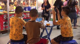 Kids in Thailand playing online games at a local food market.