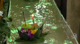 Worshippers send candle-lit baskets down a flume for Loy Krathong festival in Thailand