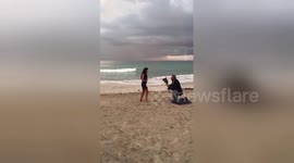Boyfriend makes surprise beachside proposal under a rainbow