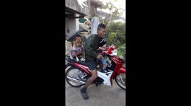 Dad teaching baby son to ride motorcycle with two pet dogs on the back