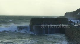 Waves smash against Cornish harbour wall