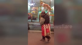 Man strolls down street in eastern Chinese city with dog balanced expertly on his head