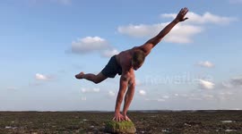 The Art of Acrobatics. One arm stand on the head on the seabed