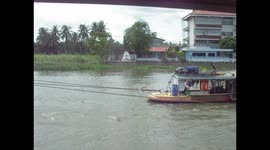 Two small boats tow a very large barge on a river.