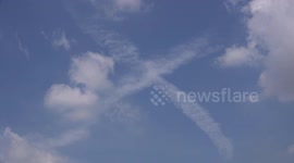 A big white X moves across a blue sky.
