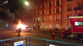 Paris riots: firefighters extinguish a burning car