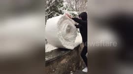 Man 'folds' snow on top of a wall into giant snowball
