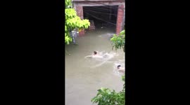 Firefighters swim through flooded road to rescue trapped girls