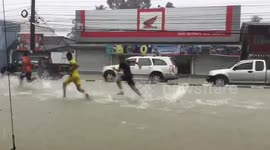 Children play on flooded road after heavy rain in southern Thailand