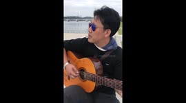 Our guide, mr Kim borrows my guitar and plays a korean song, next to the Juche tower in Pyongyang.