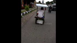 Paraylsed man pedals 3-wheel bicycle by hand to get around town