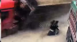 Men on scooter narrowly escape being buried by lorry tipping over on road