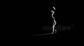 Man walks tightrope in glowing LED suit