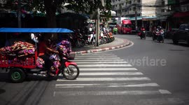 Woman balances on pile of blankets on tricycle