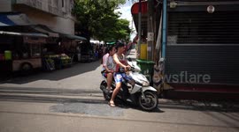 Woman riding pillion while holding fan
