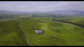 Aerial, beautiful green hills and fields and cypresses landscape in Tuscany, Italy